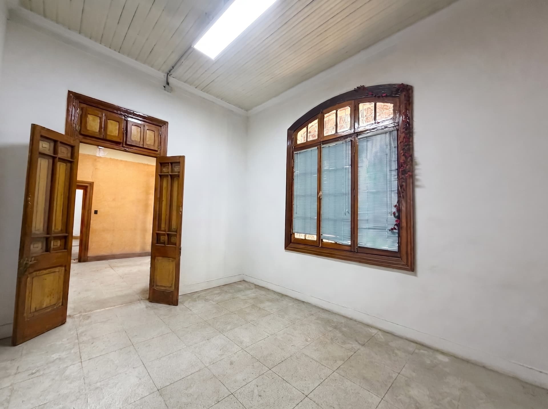 Sala de techo alto con puertas de madera originales y ventana en arco — Espacio 1, sede Salvador, Ñuñoa