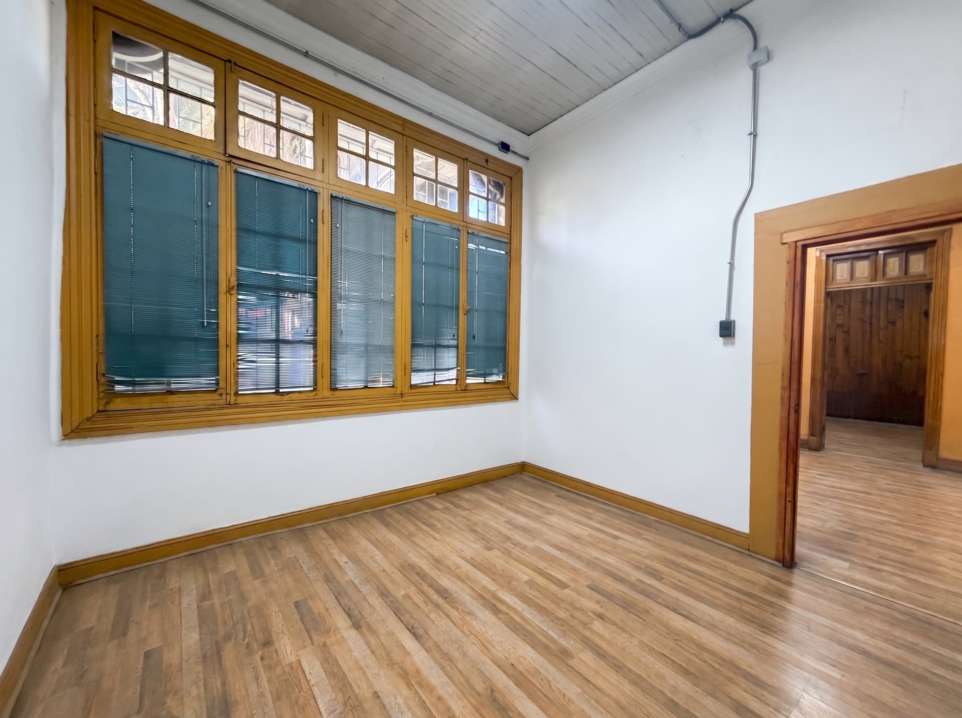 Interior de un taller luminoso con piso de madera y gran ventanal en la sede Salvador, Ñuñoa