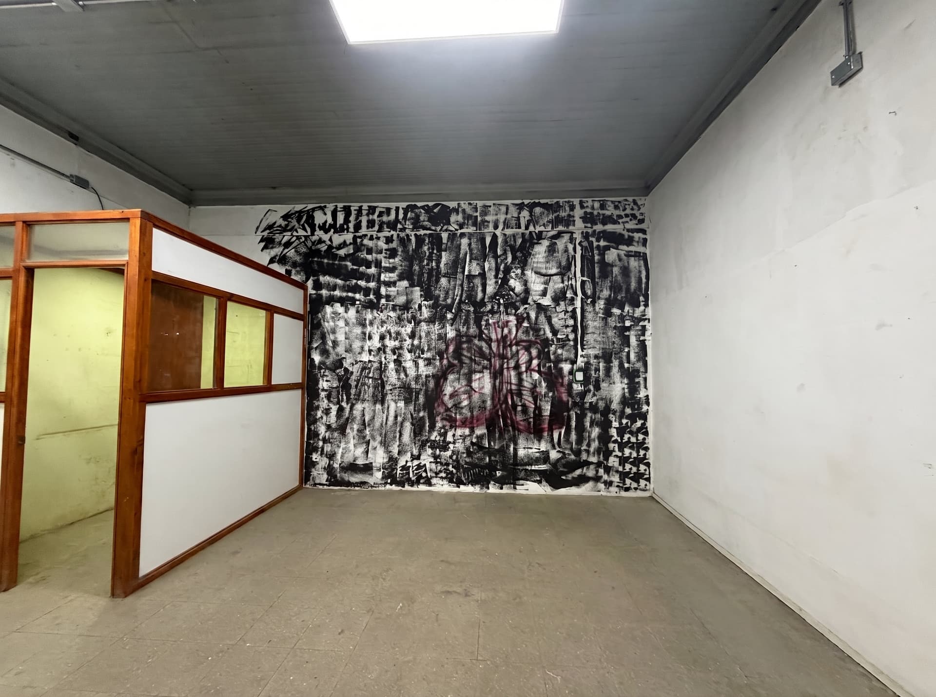 Espacio amplio de carácter industrial con muro intervenido y sector cerrado interior — Espacio 5, sede Salvador, Ñuñoa