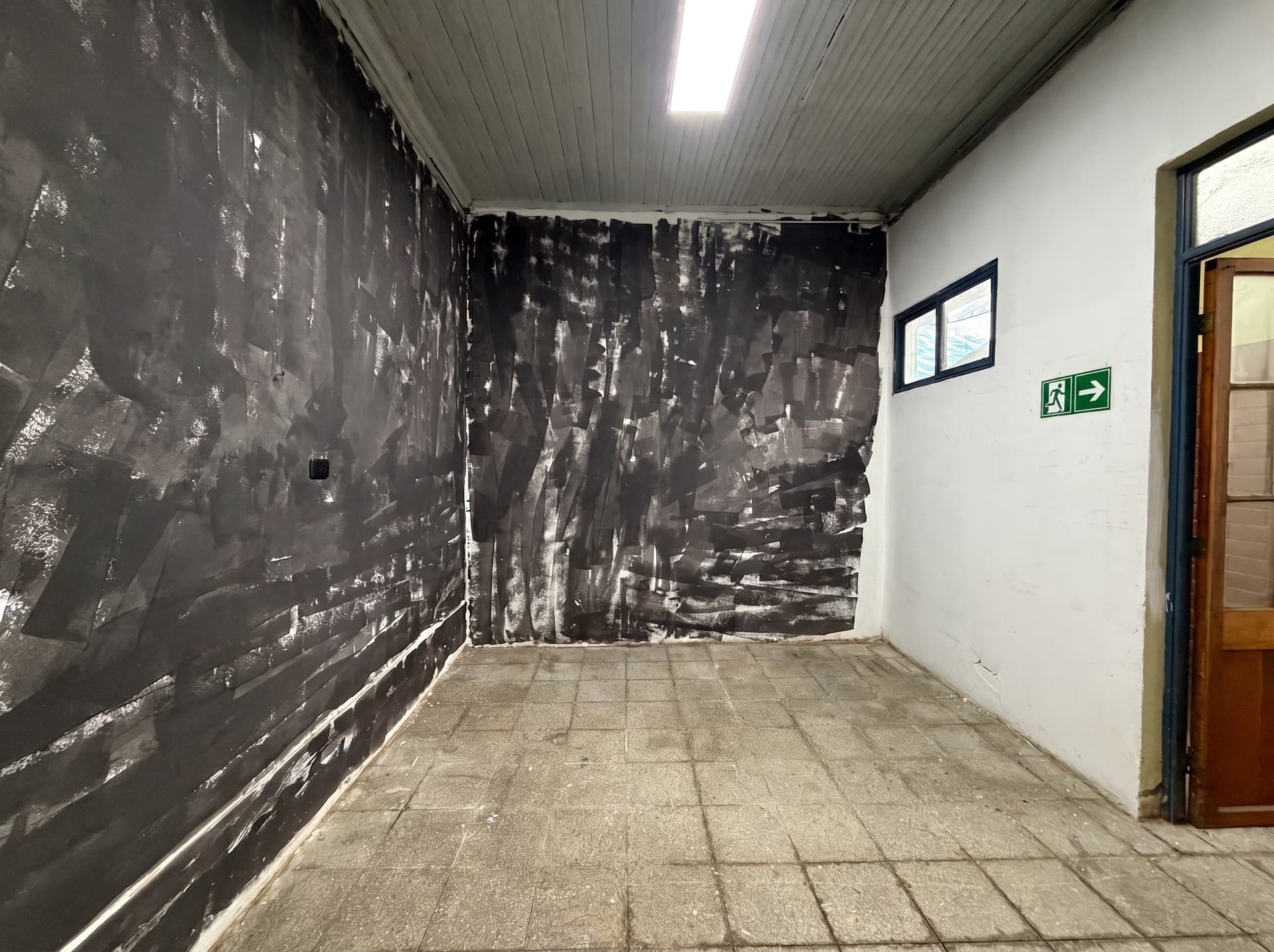 Espacio 6 en la sede Salvador, Ñuñoa — Sala de carácter industrial, con muros oscuros texturizados, piso de piedra y techo de madera. Un fondo con carácter para taller o fotografía.
