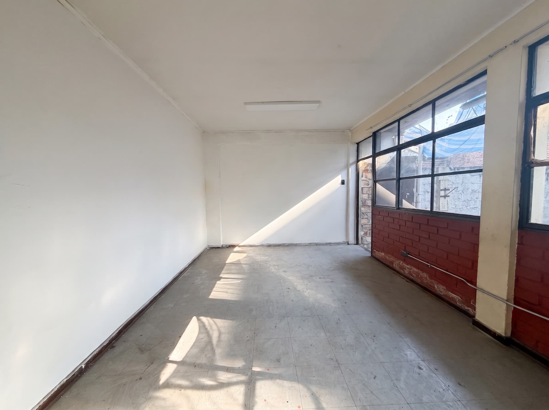 Sala amplia con ventanal completo, muro de ladrillo y luz natural directa — Espacio 7, sede Salvador, Ñuñoa